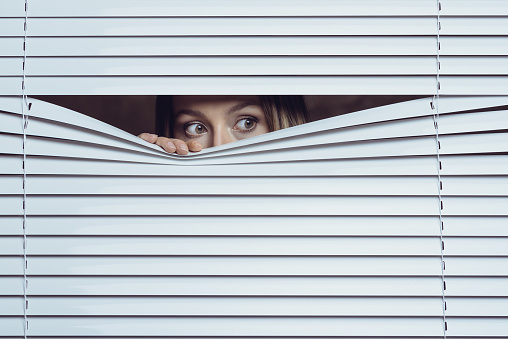 Woman peeking throuth blinds