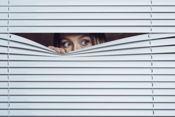 Surveillance Woman peeking throuth blinds peeking stock pictures, royalty-free photos & images