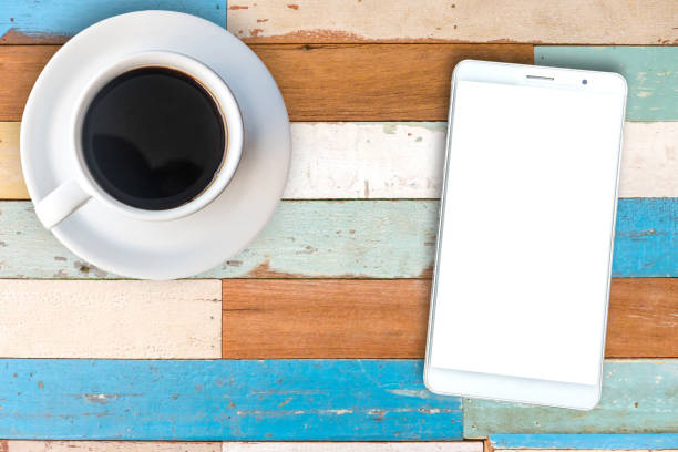 smartphone-draufsicht und schwarzen kaffee in eine weiße tasse auf holztisch. - isolated on white breakfast cafe office stock-fotos und bilder