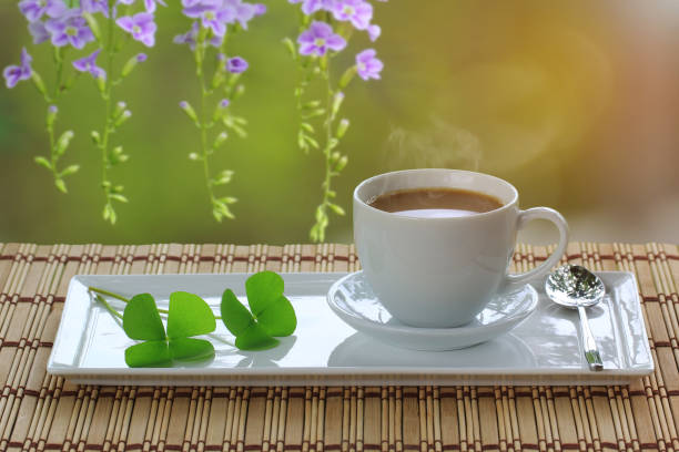 Cup of coffee and four leaf clover on the table.