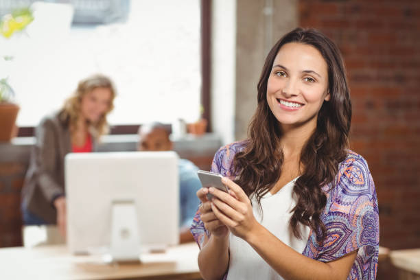 istock Smiling businesswoman using smartphone in office 671155996