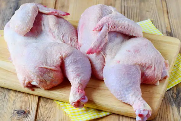 Raw chicken in halves on  wooden cutting board Step by step cooking