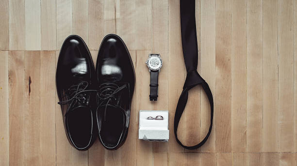 nahaufnahme des modernen bräutigam accessoires. trauringe, schwarze krawatte, lederschuhe und uhr - shoe groom wood luxury stock-fotos und bilder