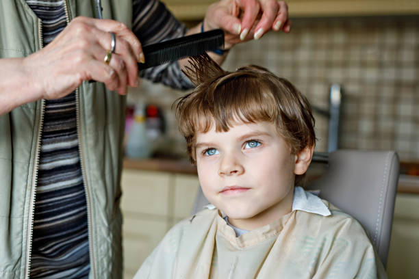 istock Beautiful kid boy with blond hairs getting his first haircut. 671173928