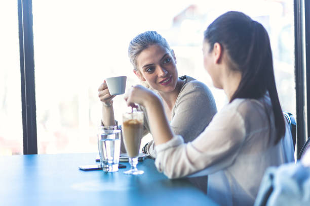 istock Young women drinking coffee and talking at cafe 671179034