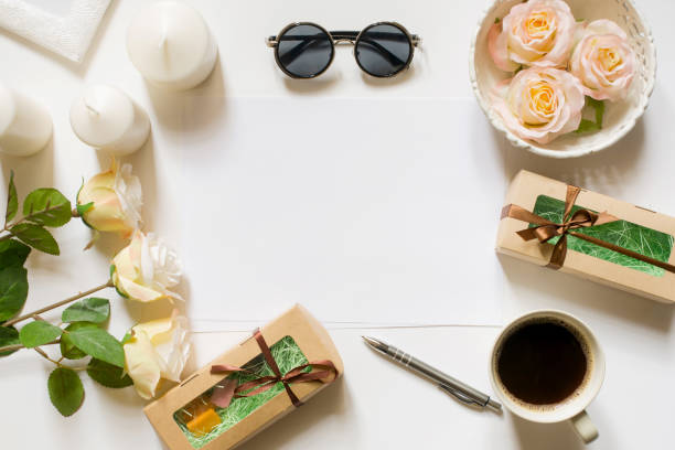 istock Empty sheet with copy space on the white desk with coffee cup, sunglasses, roses, candles and vintage white tray. Top view, flat lay, copyspace. 671183182