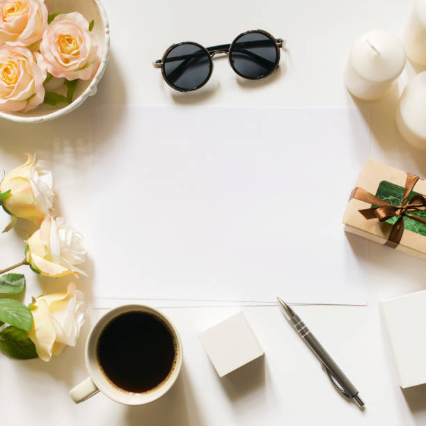 istock Square crop. Mockup. Empty sheet with copy space on the white desk with coffee cup, sunglasses, roses and vintage white tray. Top view, flat lay, copyspace. 671183450