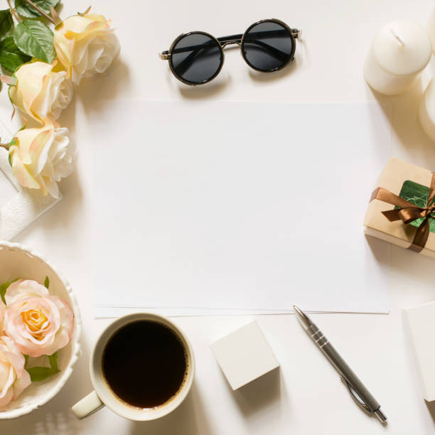 istock Square crop. Mockup. Empty sheet with copy space on the white desk with coffee cup, sunglasses, roses and vintage white tray. Top view, flat lay, copyspace. 671183514