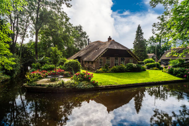 Landscape view of famous Giethoorn village with canals and rustic thatched roof houses in farm area.