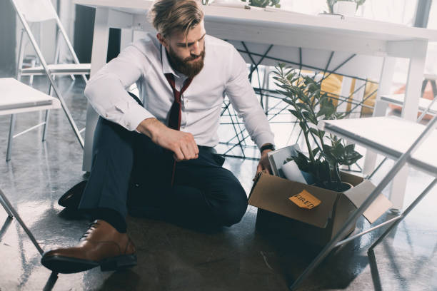 istock Young upset fired businessman sitting on floor in office 671199628