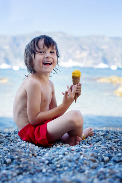 niño feliz, niño, comer helados en la playa, verano - ice cream licking little boys ice cream cone fotografías e imágenes de stock