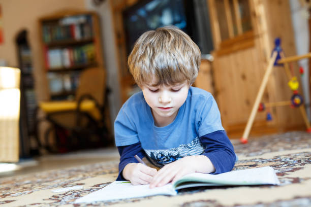 istock Happy school kid boy at home making homework 671199920