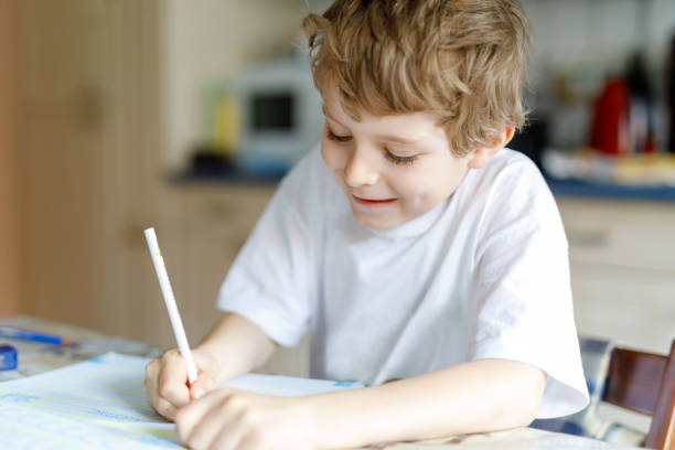 istock Happy school kid boy at home making homework 671200426