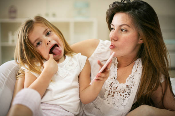 istock Smiling mother with daughter using smart phone on bed. 671203700