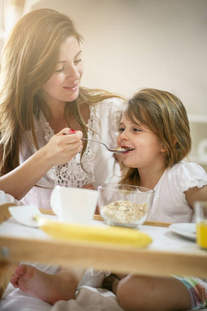 istock Mother with her little daughter having breakfast in the bed. 671204002