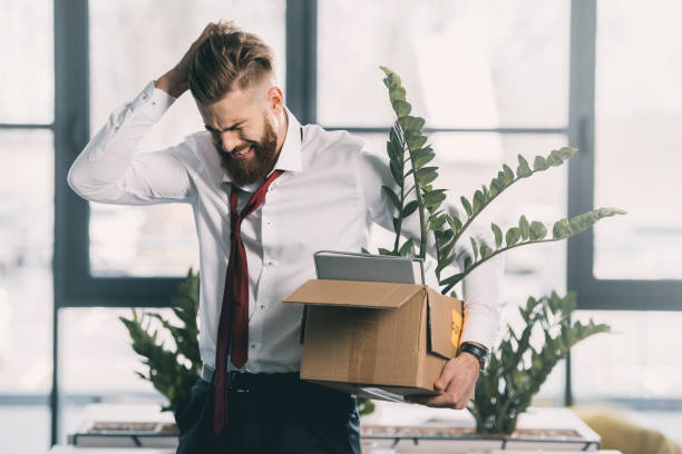 istock Young upset fired businessman with cardboard box in office 671208060