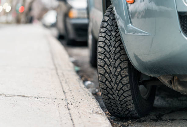 Tire turned into the curb - parking on a hill Close-up of a car parked on a hill, with the tire turned into the curb to stop  the car from rolling forward. curb photos stock pictures, royalty-free photos & images