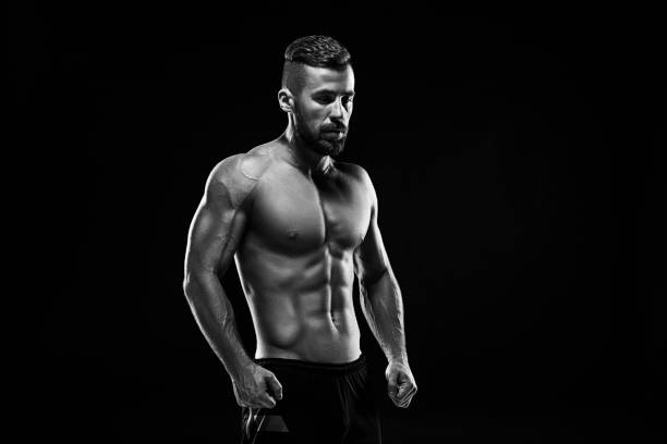 der torso der attraktiven männlichen bodybuilder auf schwarzem hintergrund - body building men flexing muscles male stock-fotos und bilder