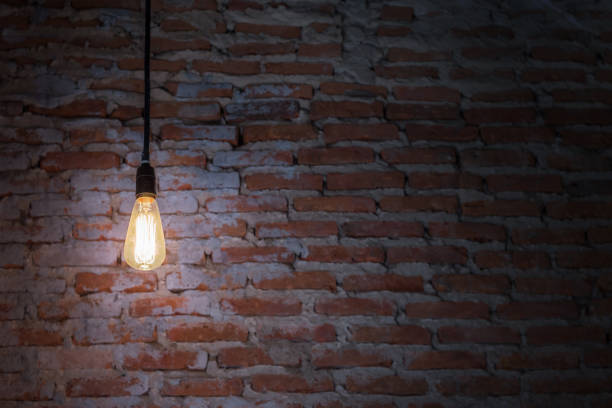 istock The bulb illuminated in the dark with brick background 671228762