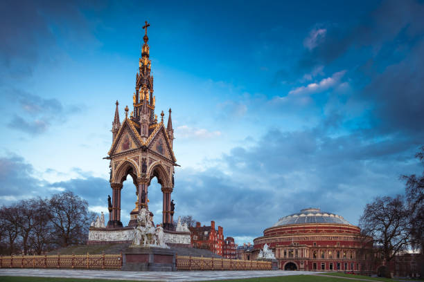 The Prince Albert Memorial The Prince Albert Memorial on Royal Albert Hall background located in the center of Kensington Gardens, London, Great Britiain royal albert hall stock pictures, royalty-free photos & images