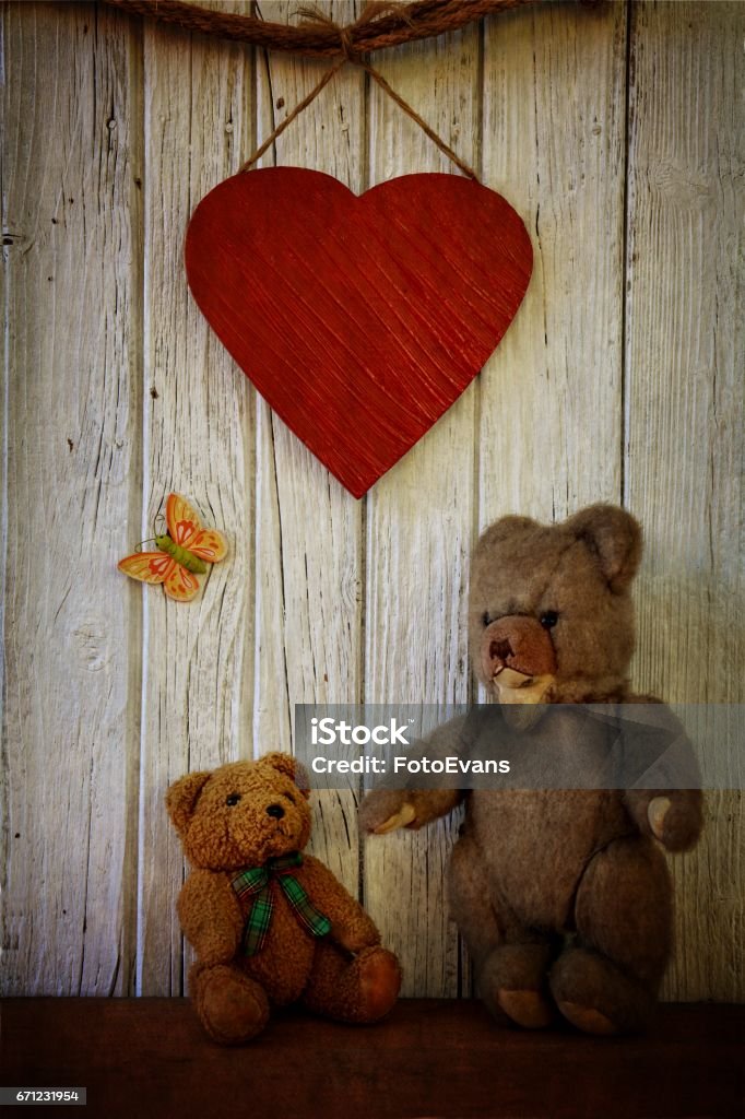 Two Teddy´s  stand before wooden wall  with big Heart Two Teddy´s  stand before old white wooden wall  with big red Heart with texture Ancient Stock Photo