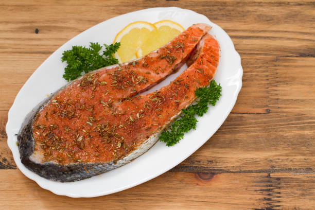 istock fresh salmon with herbs and lemon on white dish on brown background 671247134