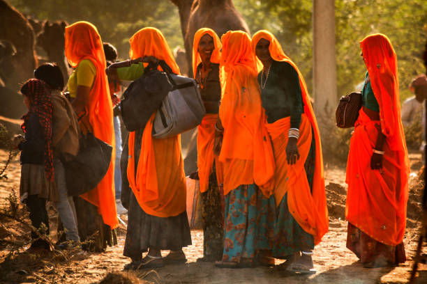 ラジャスターン州インドの農村部の女性は、激しい色の服を着てドラッププシュカルキャメルフェアに出席 - camel fair ストックフォトと画像