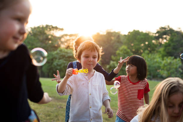 istock Group of kindergarten kids friends playing blowing bubbles fun 671256764
