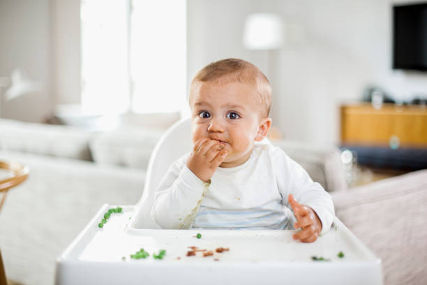 istock Baby boy eating green peas 671259136