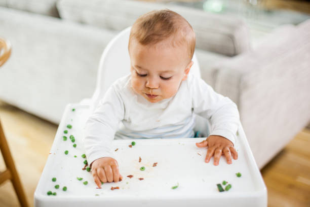 istock Baby boy eating green peas 671259166