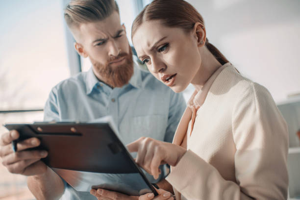 istock Young serious business people holding clipboard and discussing project 671259282