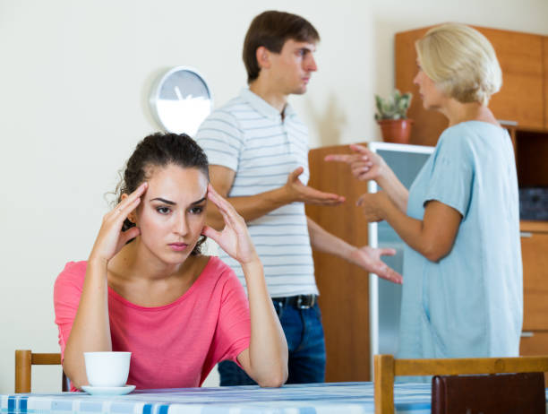 Sad young woman watching husband and mother having fight Upset girl apart from her husband and senior mother quarrelling mother in law stock pictures, royalty-free photos & images