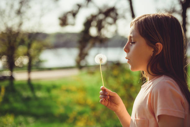 istock Girl blowing a dandelion 671260096
