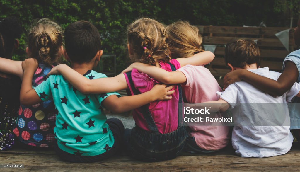 Group of kindergarten kids friends arm around sitting together Child Stock Photo
