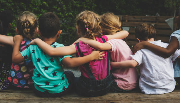 Group of kindergarten kids friends arm around sitting together Group of kindergarten kids friends arm around sitting together arm around stock pictures, royalty-free photos & images