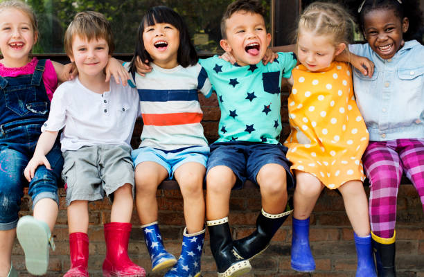 Group of kindergarten kids friends arm around sitting and smiling fun Group of kindergarten kids friends arm around sitting and smiling fun preschool stock pictures, royalty-free photos & images