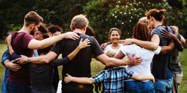 Group of people huddle together in the park Group of people huddle together in the park different families stock pictures, royalty-free photos & images