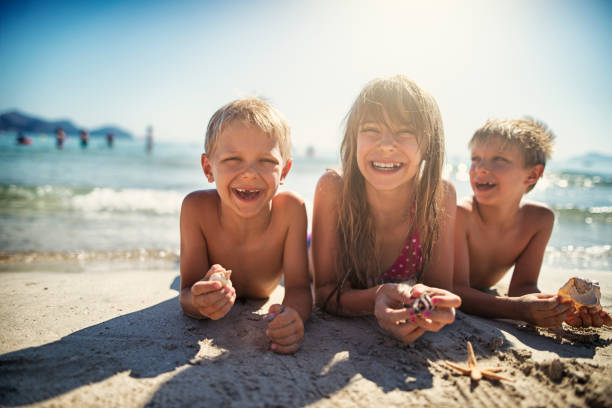 kids playing with sea shells on sandy beach - carefree joy children only pre adolescent child imagens e fotografias de stock