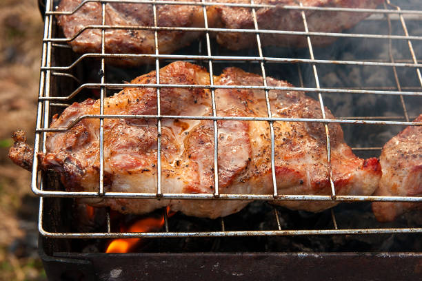 istock Pork steak cooking on an open flame grill. 671282288