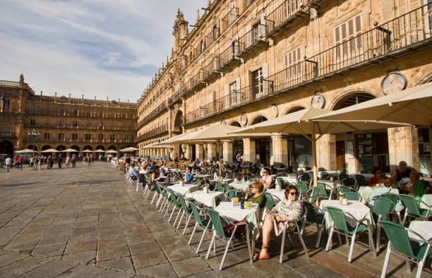 Madrid, Spain - June 2, 2016: People sit and walk on the historical Plaza Mayor,or main square, with tables and chairs of a restaurant in the old center of Salamanca, Spain on June 2, 2016