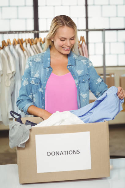istock Woman separating clothes from donation box in office 671290816