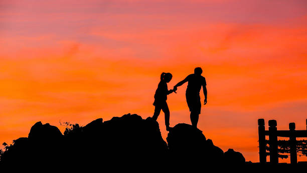 istock silhouette of couple help each other trust assistance in sunset 671291254