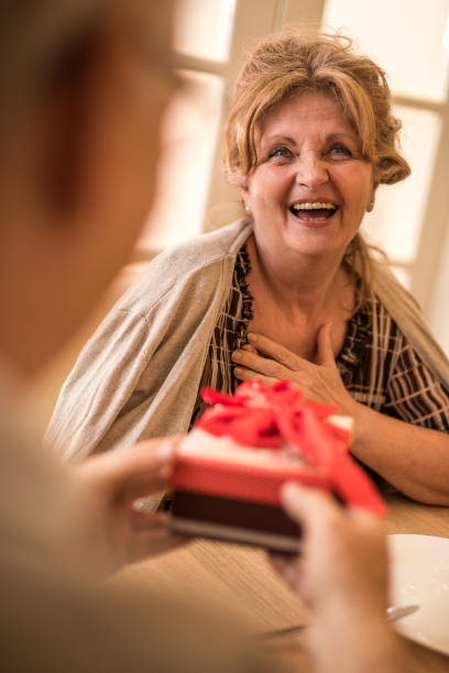 istock Surprised mature woman receiving gift box from her husband. 671299084