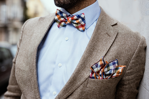 Close up of well dressed man's torso. Guy wearing jacket, shirt and colorful handkerchief and bow tie