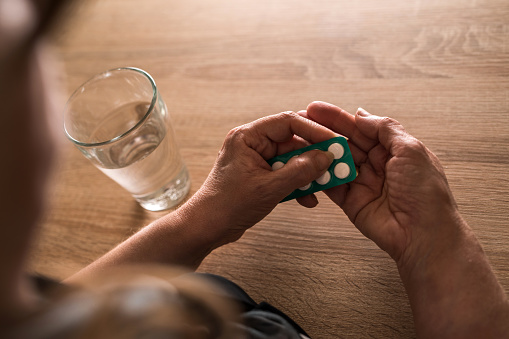 Close up of elderly woman taking a medicine out of blister pack. Close up of elderly woman taking a medicine out of blister pack.