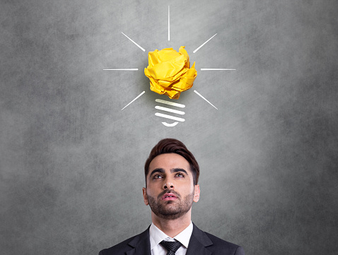 Businessman looking at crumpled paper light bulb icon