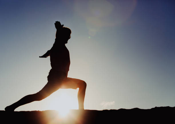 istock Silhouette of young man doing yoga at sunset 671324446