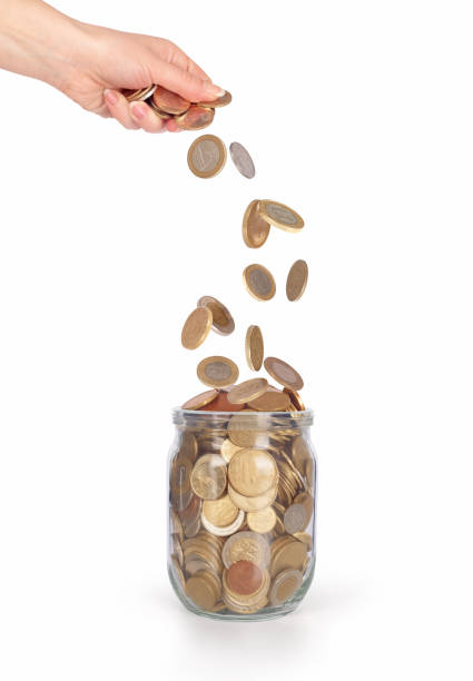 istock coins falling into the glass jar from womens hand isolated 671327802