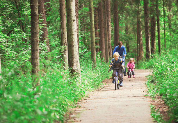 istock father with two kids riding bikes in nature 671328360