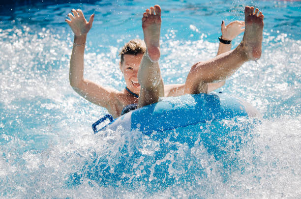 casal engraçado tomar uma água rápida passeio em um flutuador de salpicos de água. conceito de férias de verão. - boia equipamento de desporto aquático - fotografias e filmes do acervo